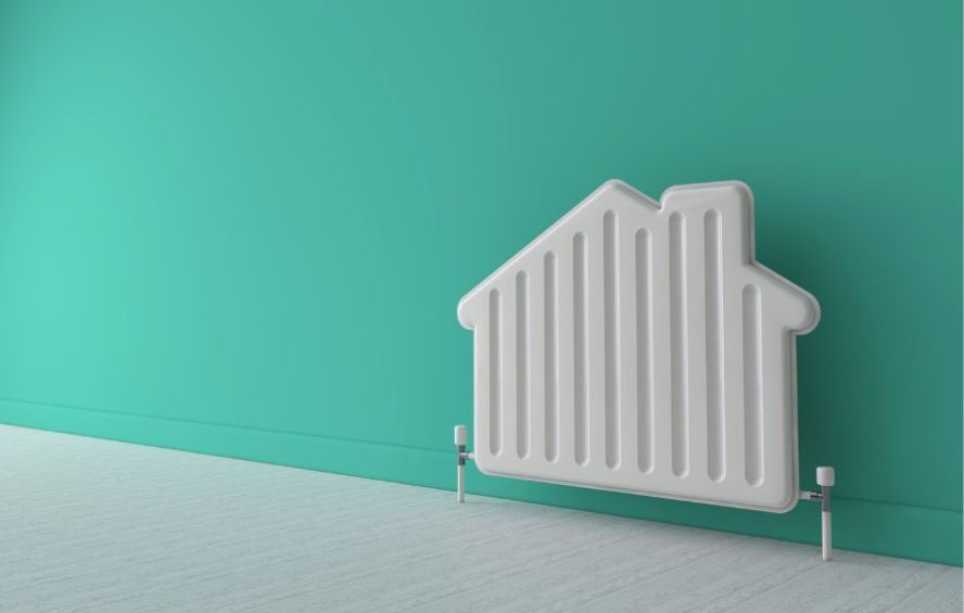 Ein weißer Heizkörper (Radiator) an einer Wand vor grünem Hintergrund – Symbolbild für das Thema Heizung